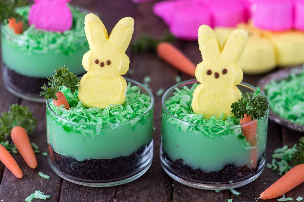 Peeps bunny pudding dirt cups with oreos, pudding, coconut, a mini carrot and a peep in a glass dessert bowl