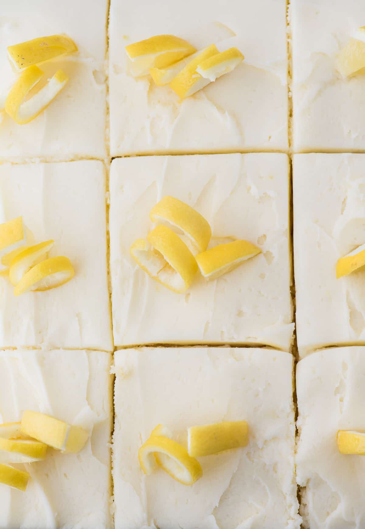 lemon cake with white frosting and lemon peels cut into pieces
