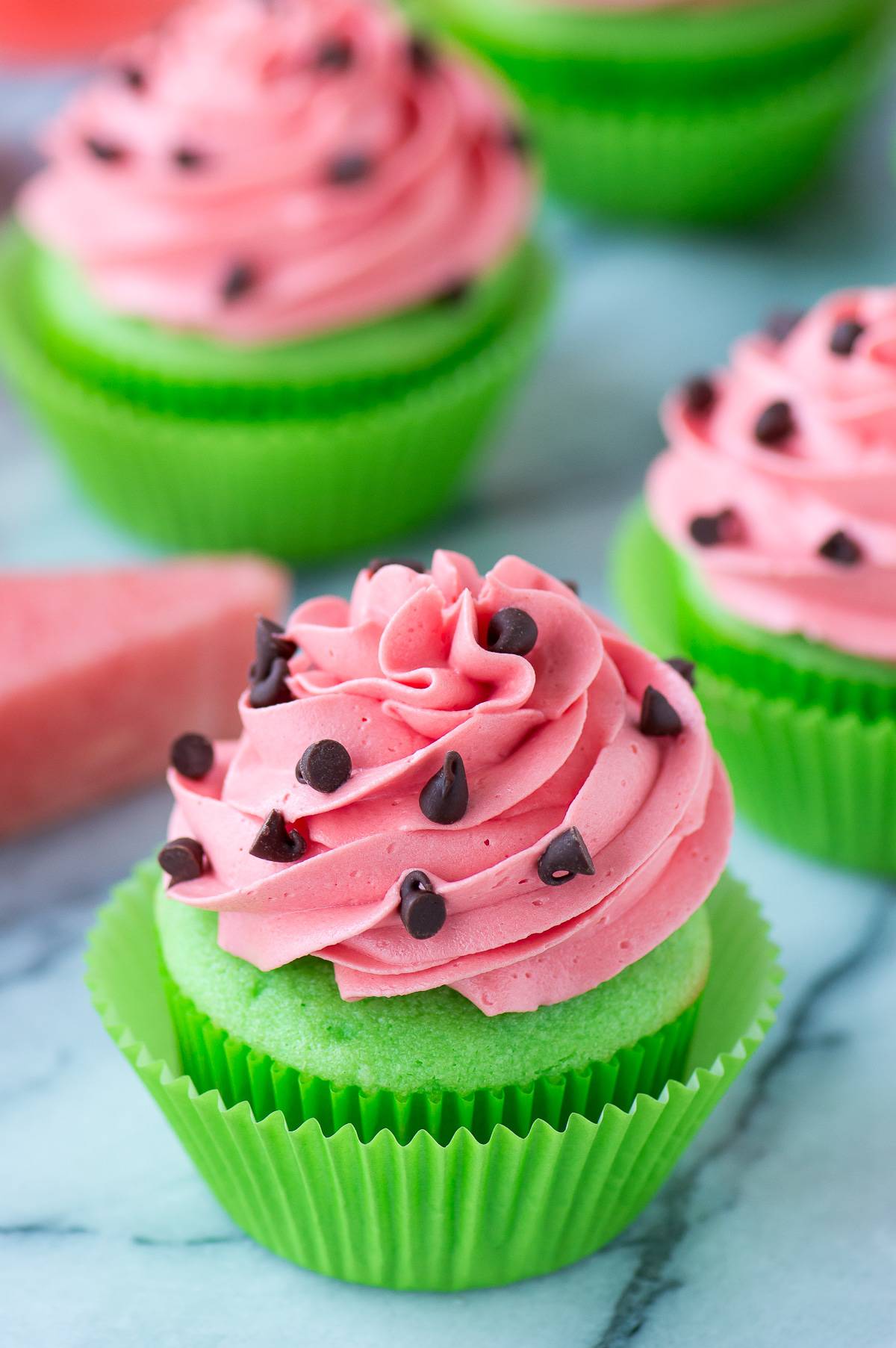 green cupcakes with pink watermelon frosting with mini chocolate chips for watermelon seeds on marble background