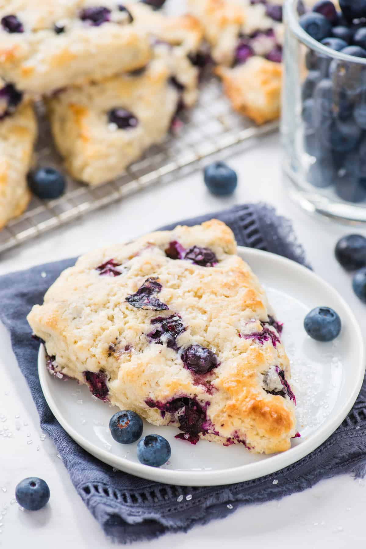 blueberry scone on white plate and blue napkin