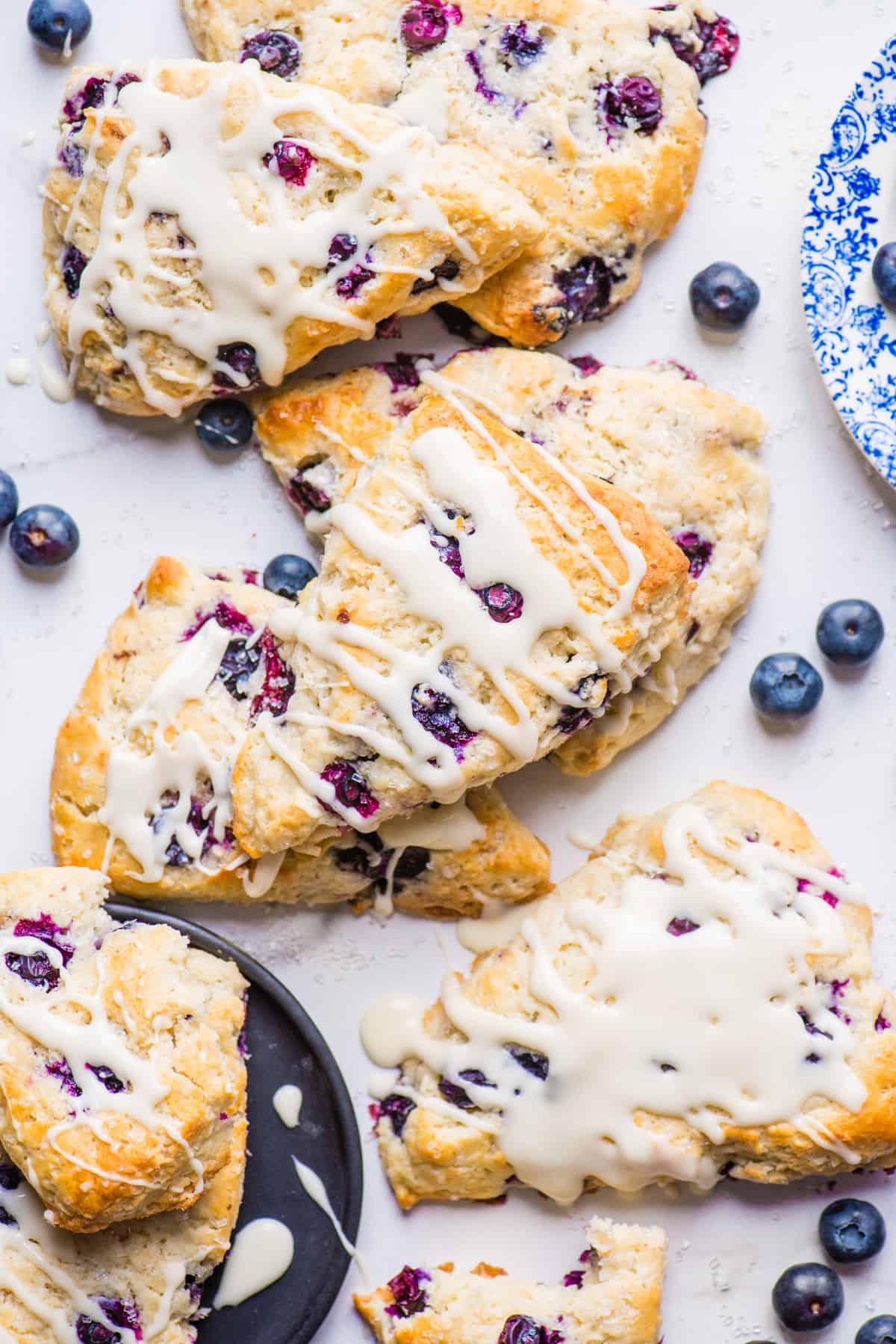 blueberry scones with white icing arranged on white background