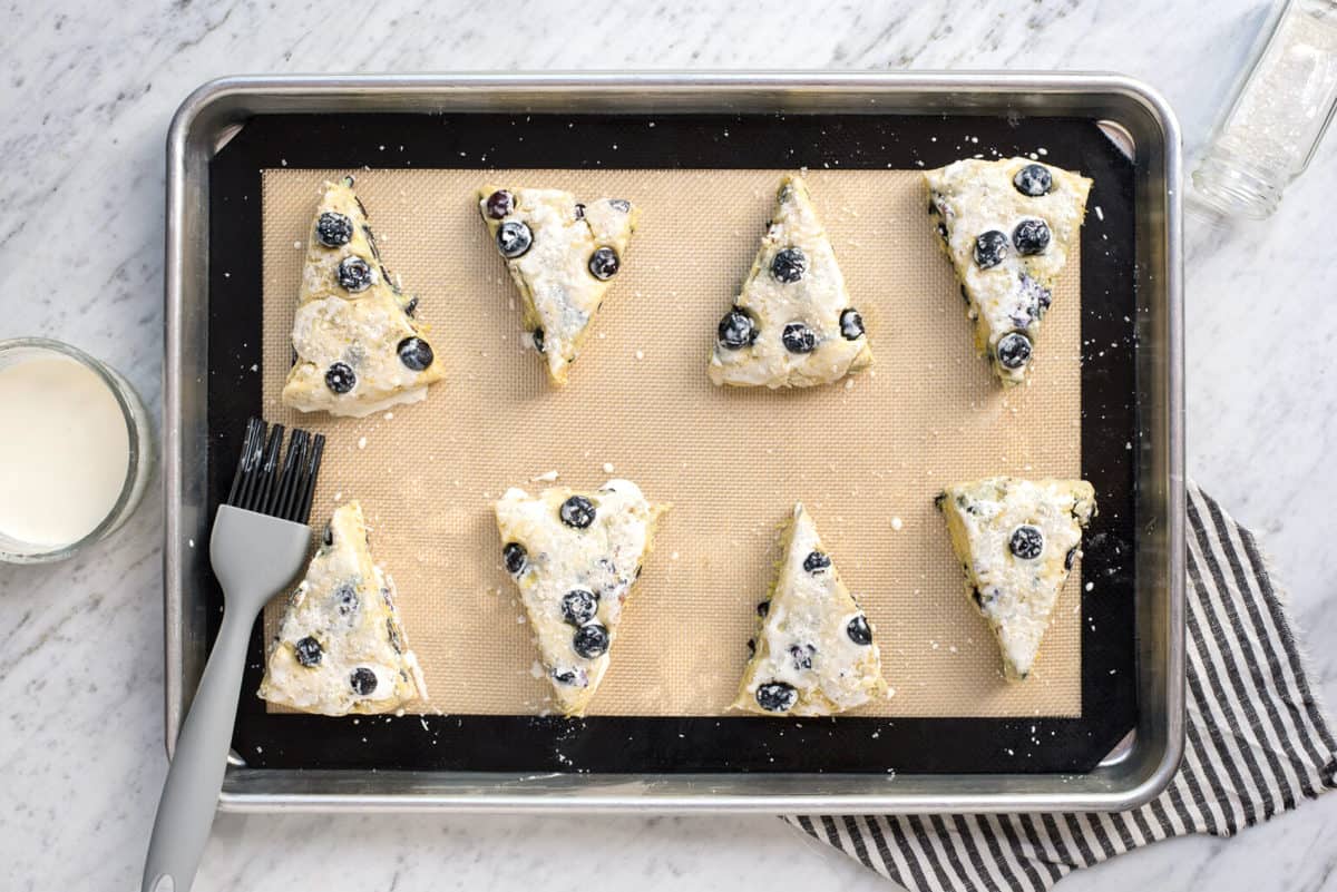 eight blueberry scones with heavy cream wash on silicone baking mat