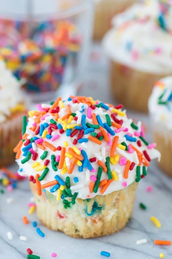 funfetti cupcake with white frosting topped with rainbow sprinkles