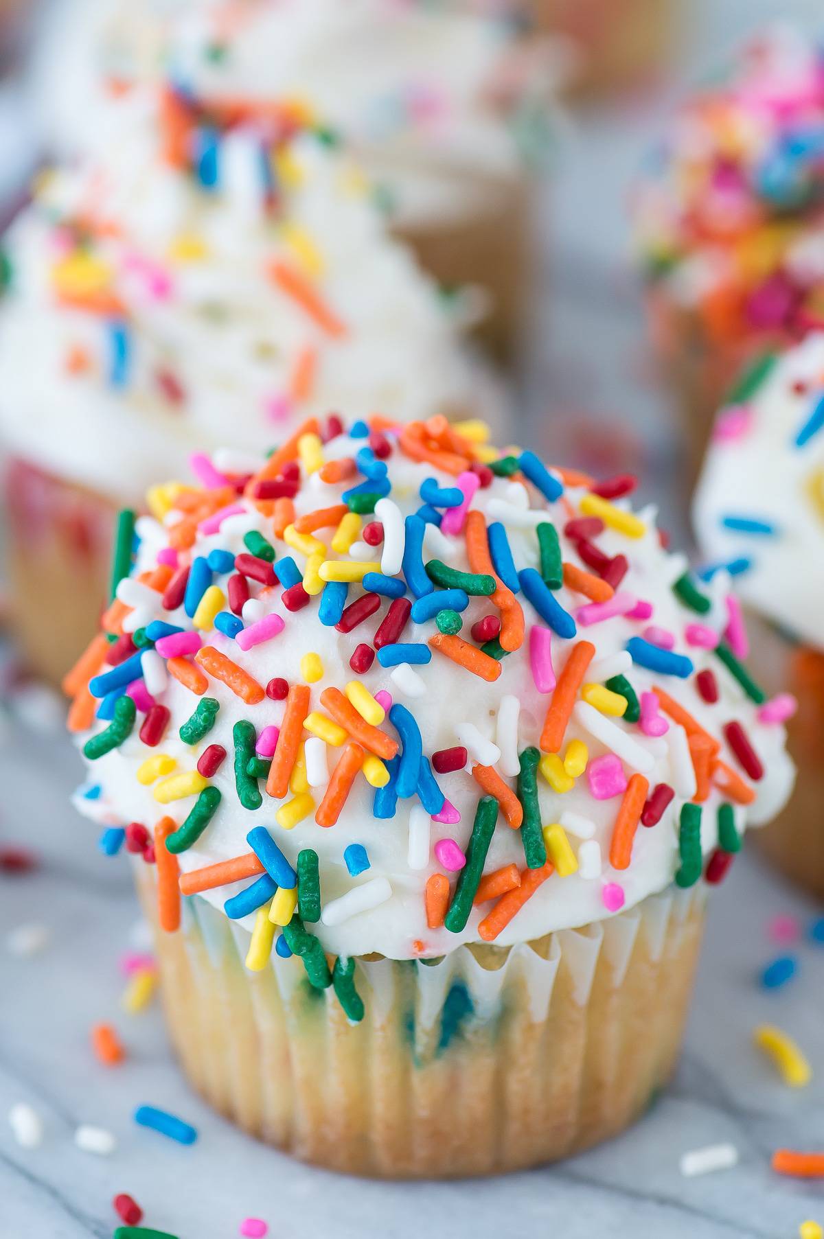 funfetti cupcake with white frosting topped with rainbow sprinkles