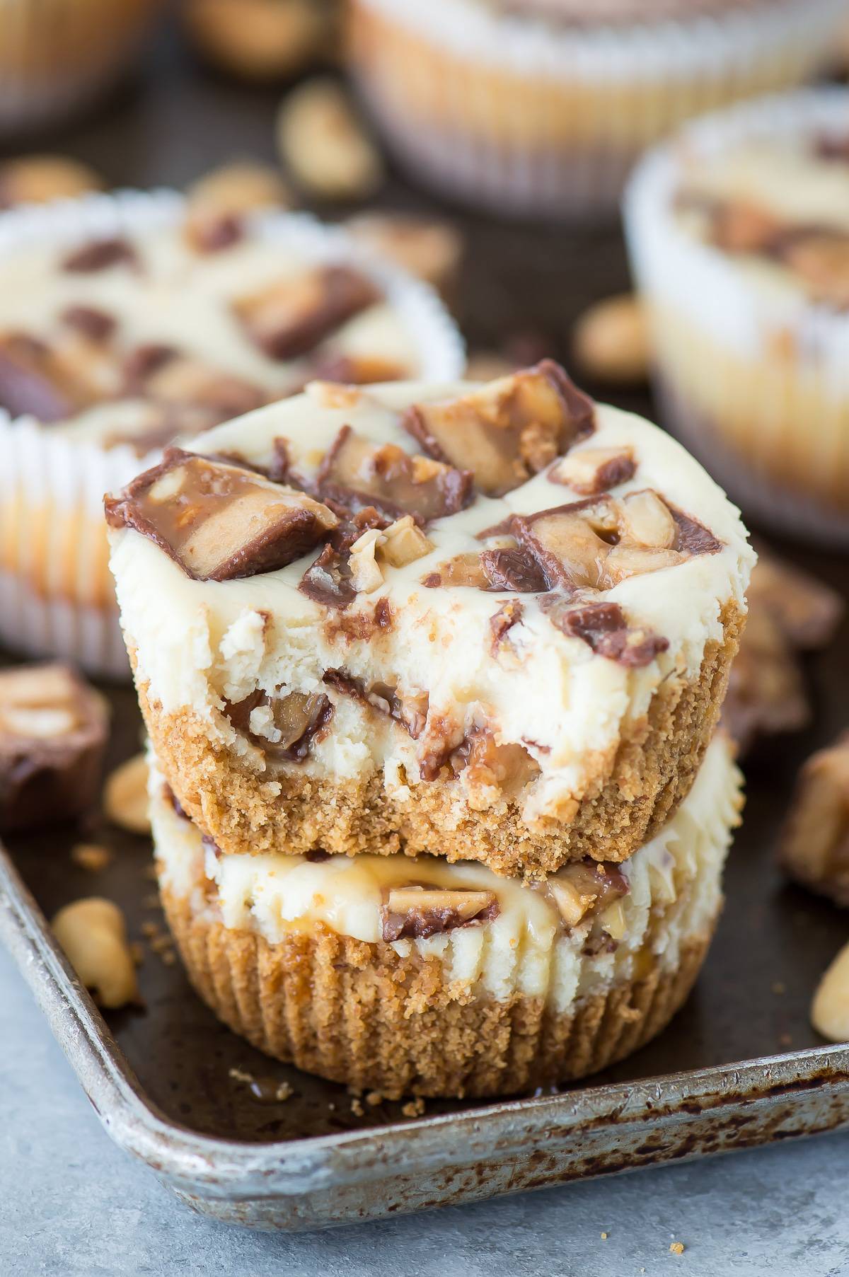 mini snicker’s cheesecakes stacked 2 high with bite taken out of top cheesecake