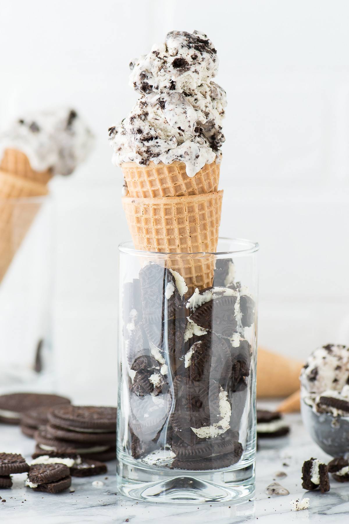 3 Ingredient Oreo Ice Cream in two waffle cones inside of a glass full of broken oreos.