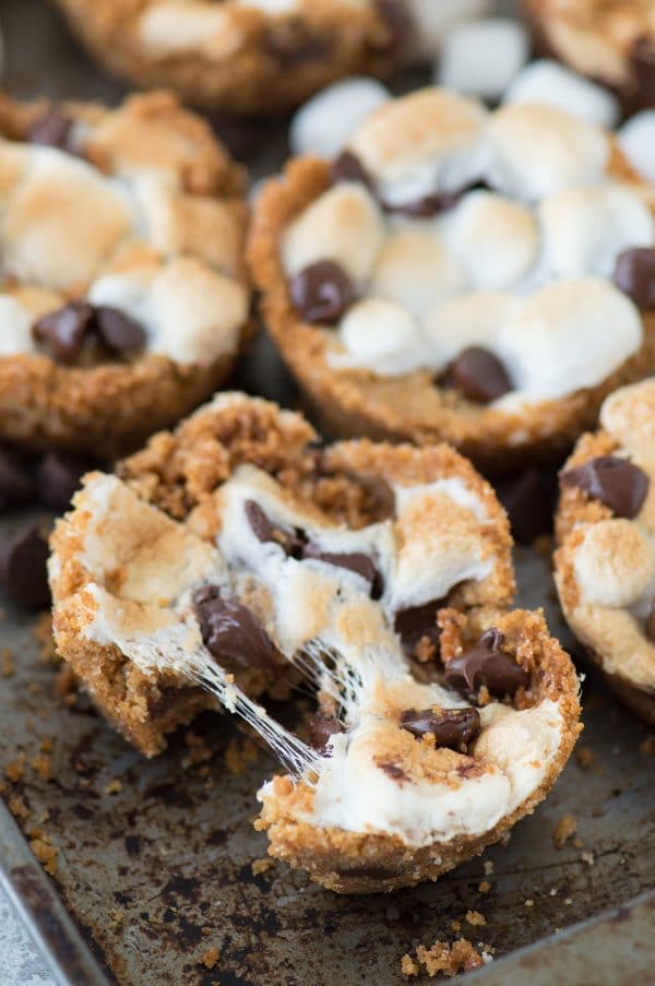 5 ingredient indoor S’mores Cups! Make these in a regular muffin pan. Like a cross between s'mores cookies and s'mores cupcakes! Six homemade S’mores Cups on a baking sheet.