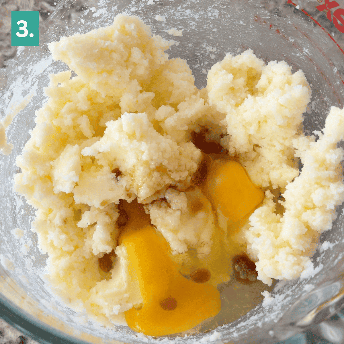 A glass bowl contains creamed butter and sugar with two cracked eggs and vanilla extract on top, ready to be mixed for caramel apple snickerdoodles. A green box with the number 3 is in the corner.
