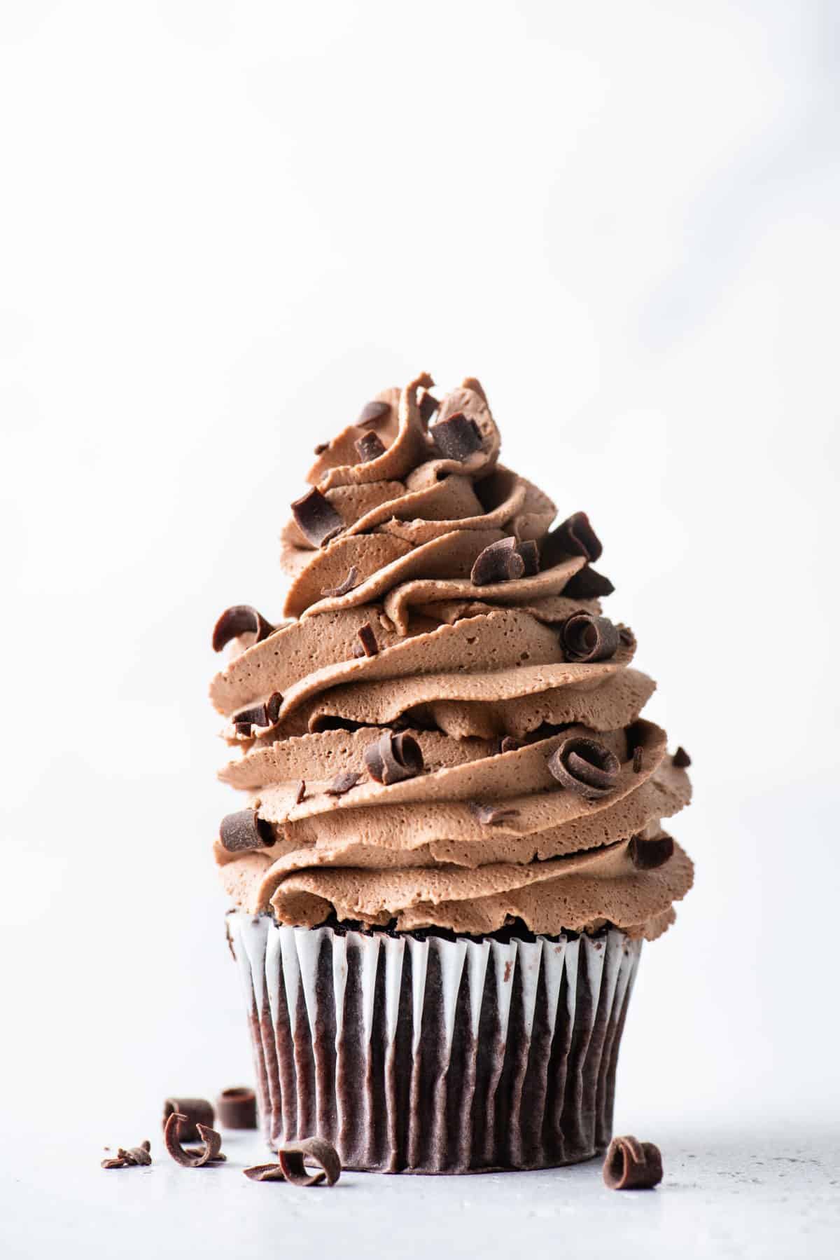 chocolate whipped cream piped onto chocolate cupcakes with chocolate shavings sprinkled on top