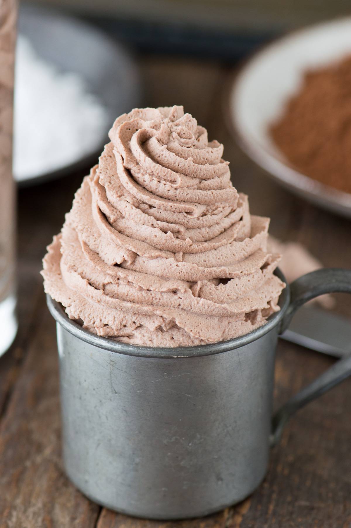 chocolate whipped cream piped into metal cup on wood background
