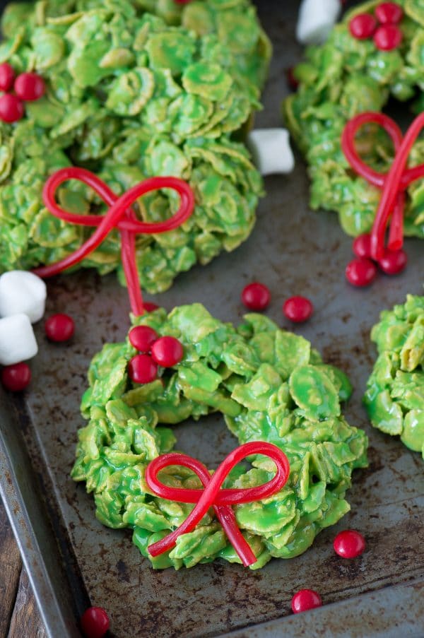 食用のtwizzlersが付いているコーンフレークとなされる緑のクリスマスの花輪のクッキーは金属表面の弓