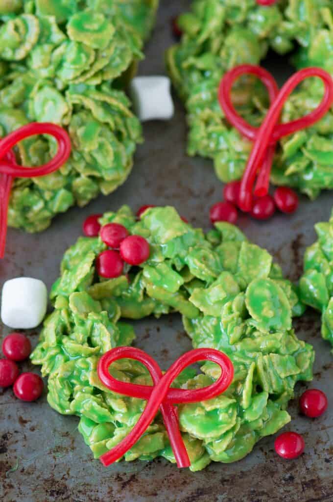 grüne Weihnachtskranzplätzchen aus Cornflakes mit essbarem Twizzlerbogen auf Metalloberfläche