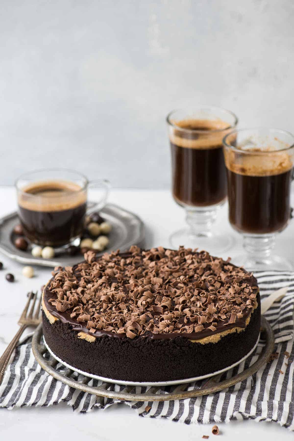 espresso cheesecake on metal stand on striped towel with coffee cups in the background