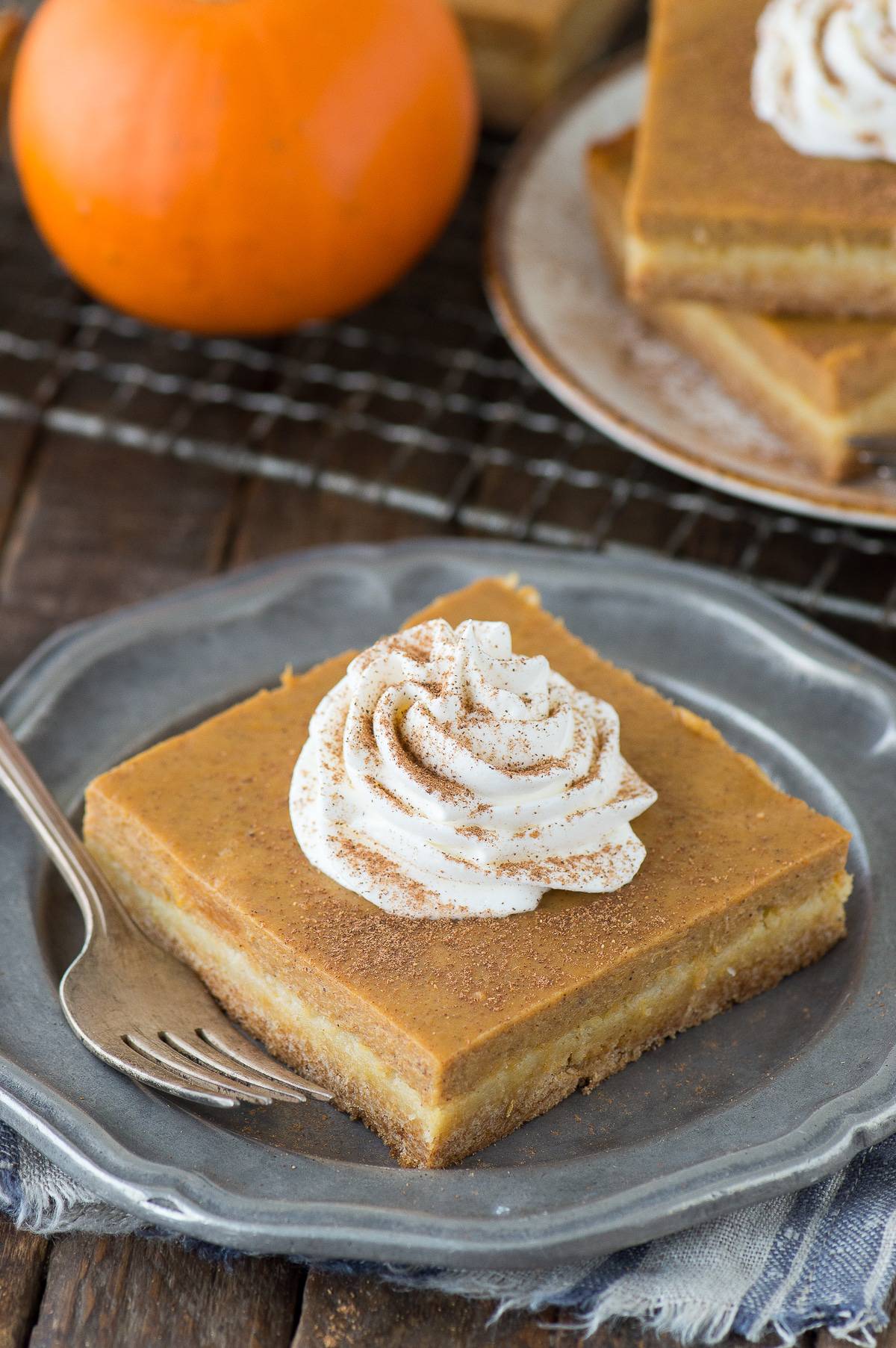 pumpkin pie bar on metal plate with dollop of whipped cream on top