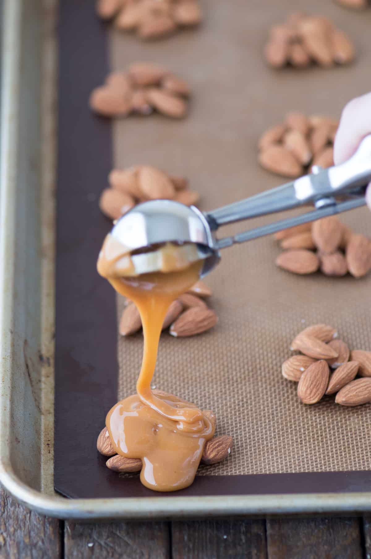 almond cluster with spoon drizzling caramel over it