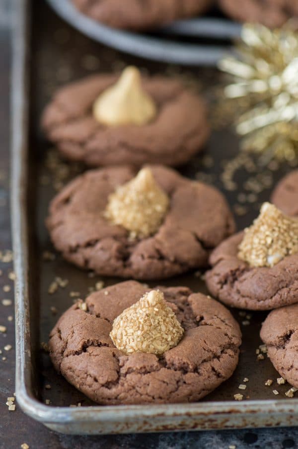 These Midnight Kiss Cookies are the best New Year’s Eve cookie! They are a spin on everyone’s favorite peanut butter blossoms, with a chocolate cookie base and gold hershey’s kisses!