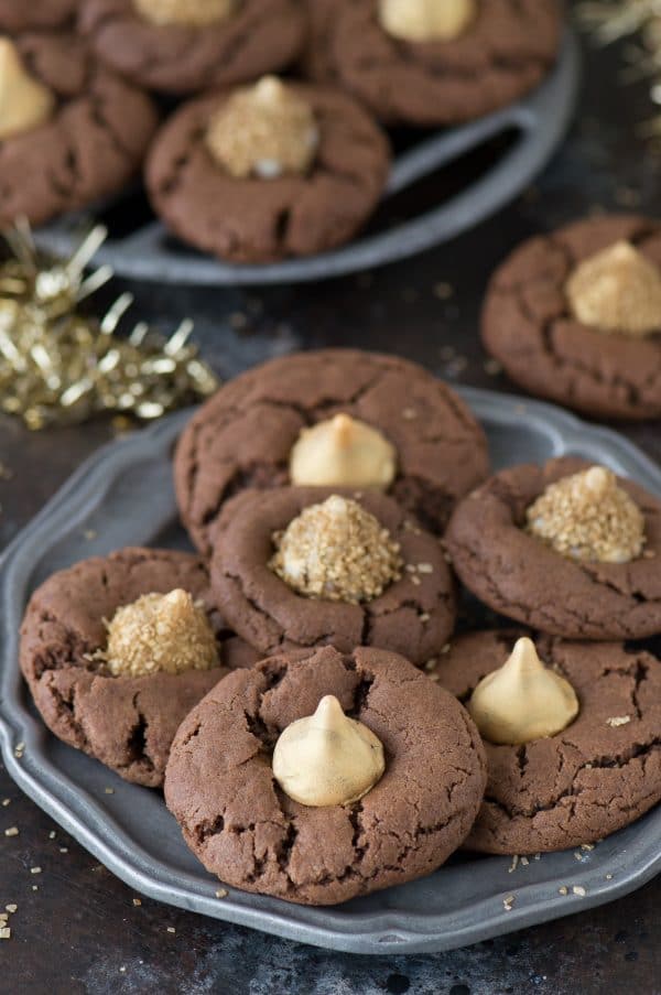These Midnight Kiss Cookies are the best New Year’s Eve cookie! They are a spin on everyone’s favorite peanut butter blossoms, with a chocolate cookie base and gold hershey’s kisses!