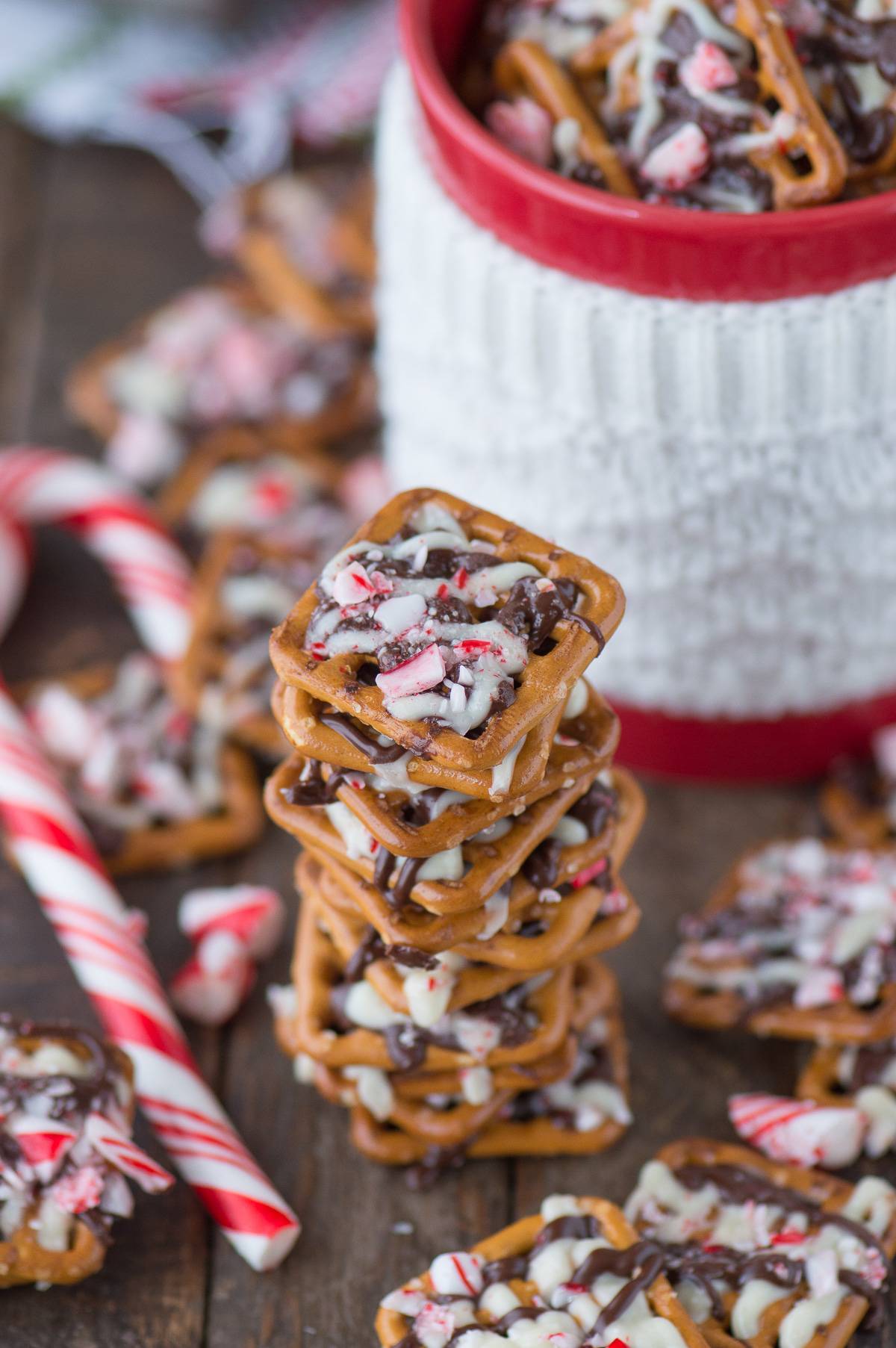 peppermint bark pretzels on wood background with red and white mug in the background