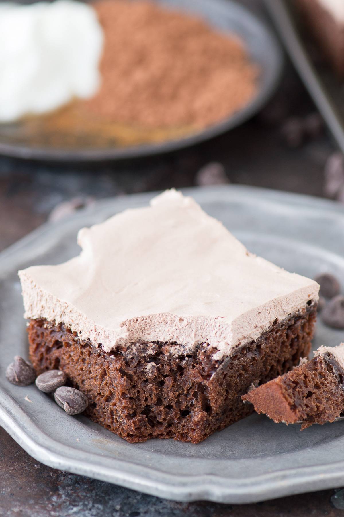 slice of healthy chocolate fudge with bite removed on metal plate with chocolate chips on plate