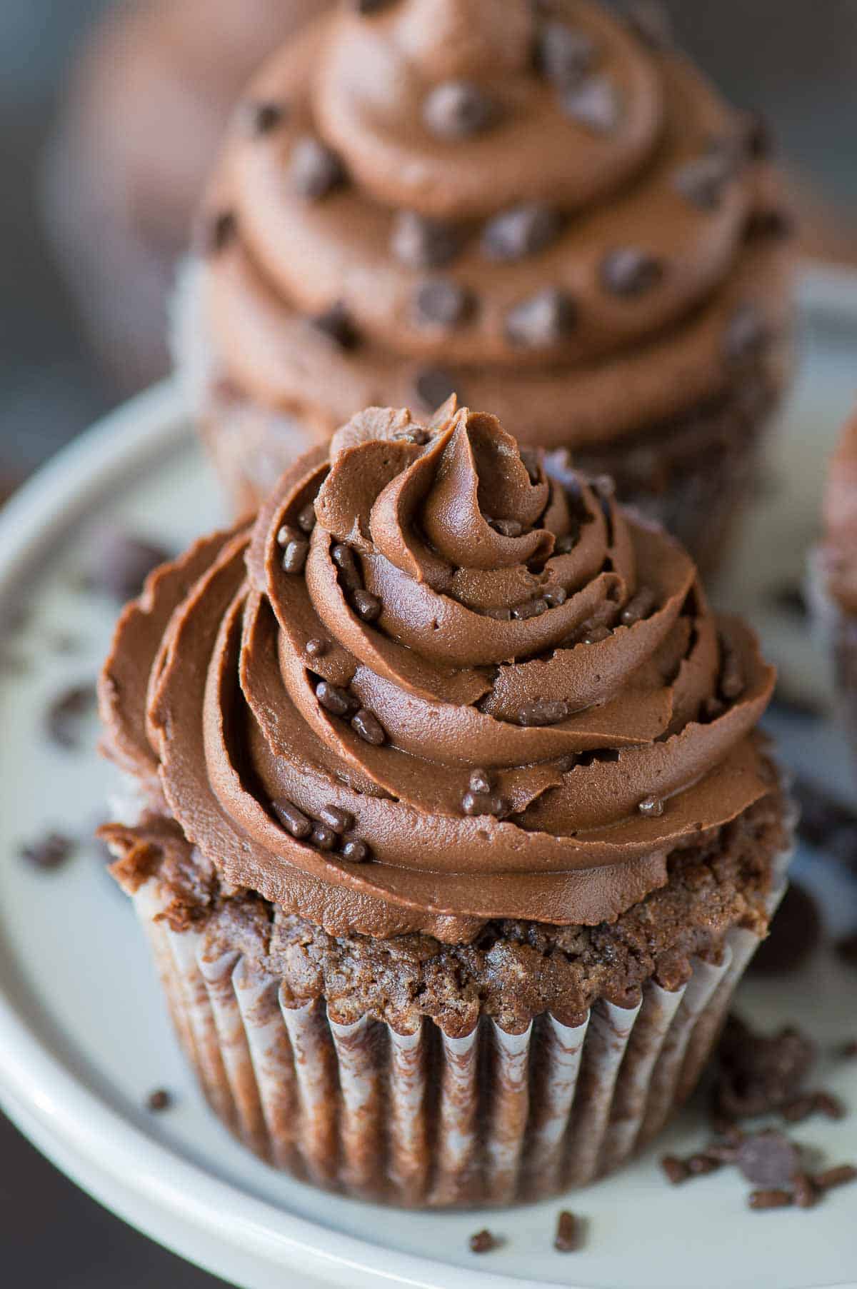 chocolate cupcake with chocolate frosting on gray cake stand