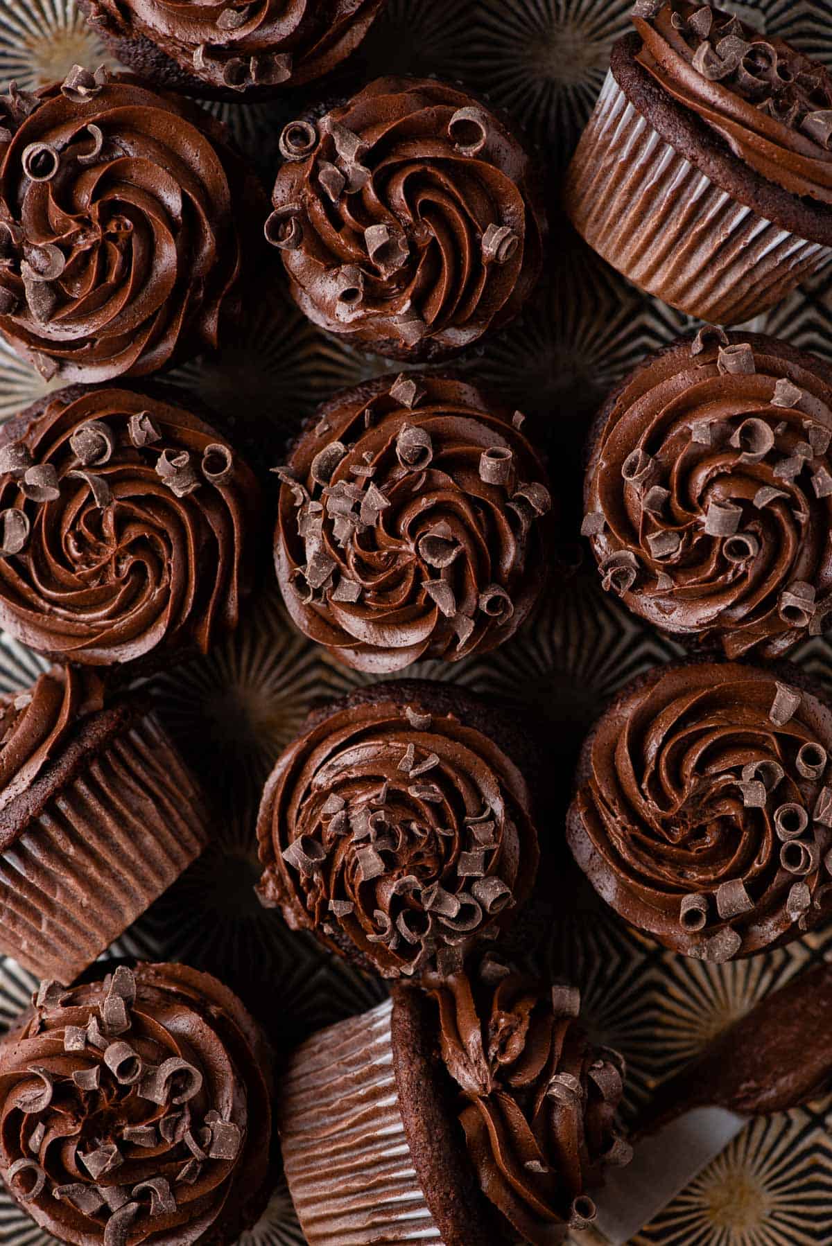 aeriel shot of chocolate cupcakes with chocolate frosting arranged in a grid pattern on metal surface