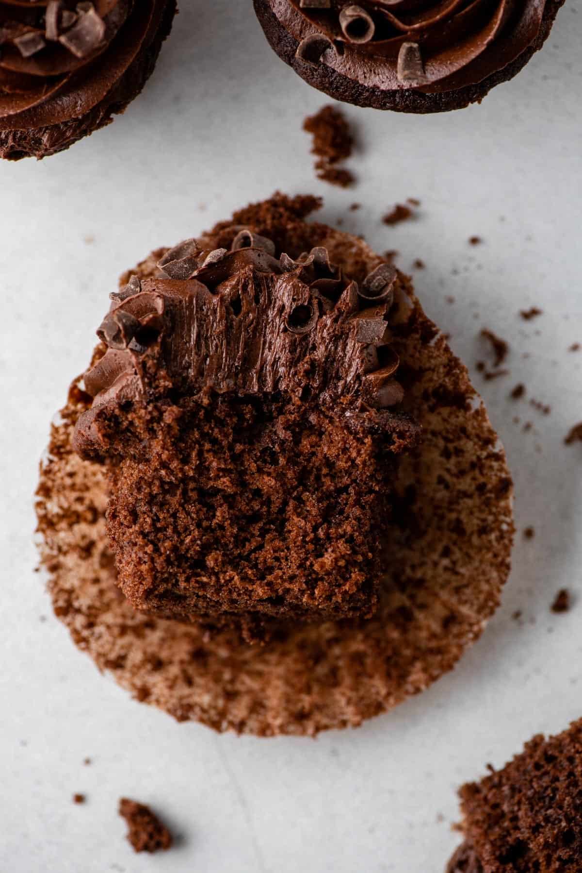 chocolate cupcake laying on it’s side with a bite removed on gray background