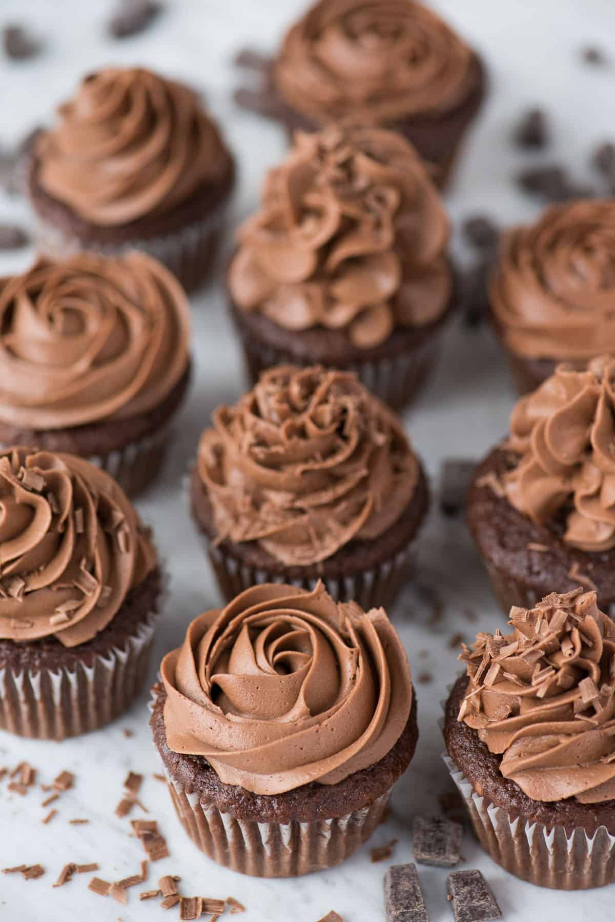 chocolate cupcakes with chocolate frosting in a grid on white background