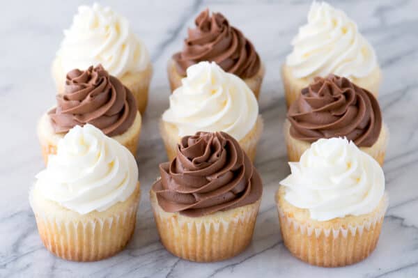 9 vanilla cupcakes with chocolate and white frosting on marble background