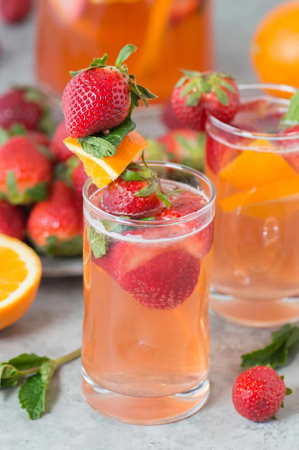 strawberry sangria in clear glass with skewer of strawberries, oranges and mint as garnish