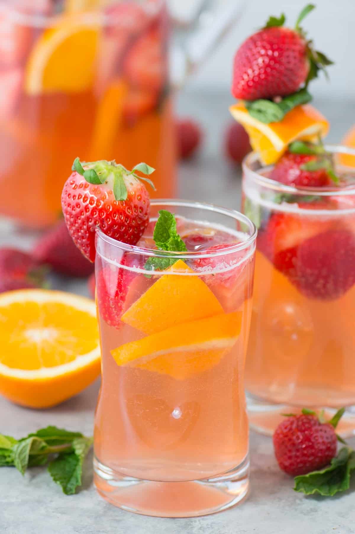strawberry sangria in clear glass with strawberries, oranges and mint as garnish