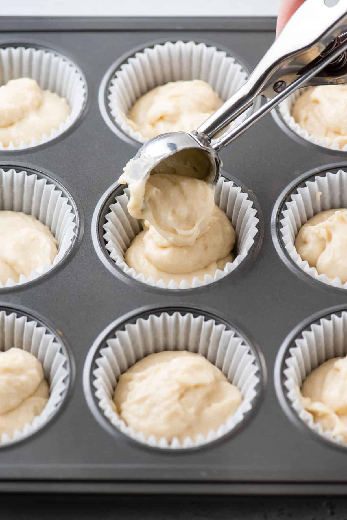 vanilla cupcake batter being scooped into cupcake pan