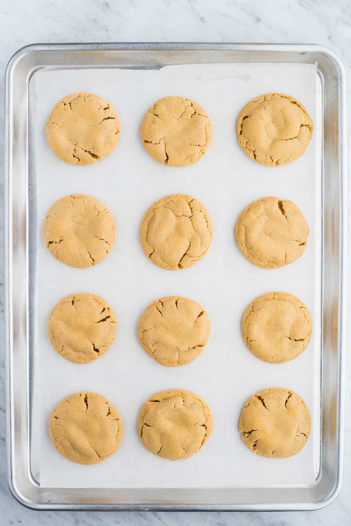 peanut butter cookies evenly spaced on white parchment paper on baking sheet