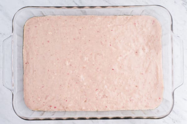 strawberry cake batter in glass pan on white background