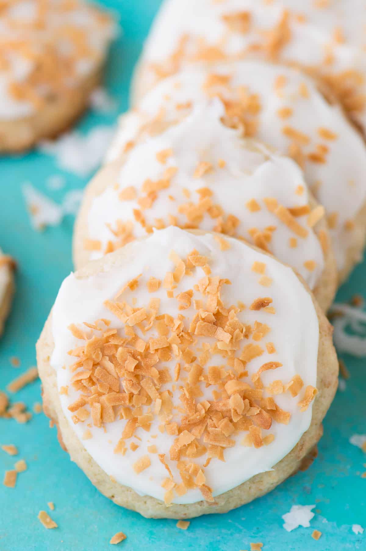 coconut cookies with white frosting on teal background