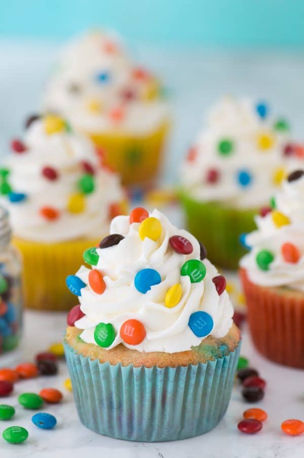 Loaded M&M cupcakes! Moist vanilla cupcakes with mini M&Ms in the batter, topped with vanilla buttercream and more mini M&Ms!