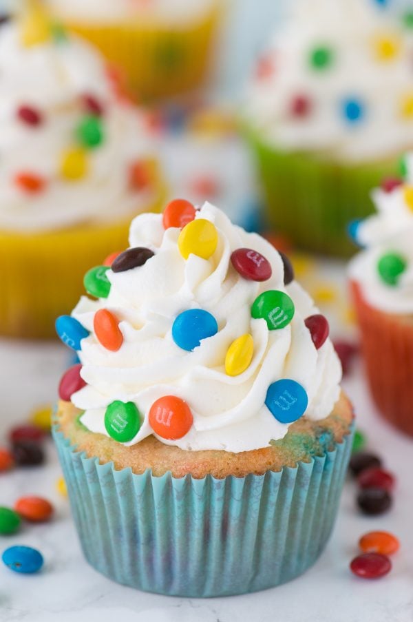 Loaded M&M cupcakes! Moist vanilla cupcakes with mini M&Ms in the batter, topped with vanilla buttercream and more mini M&Ms!