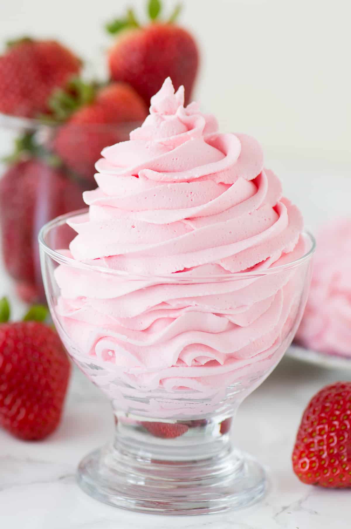 strawberry whipped cream piped into clear glass with strawberries in the background