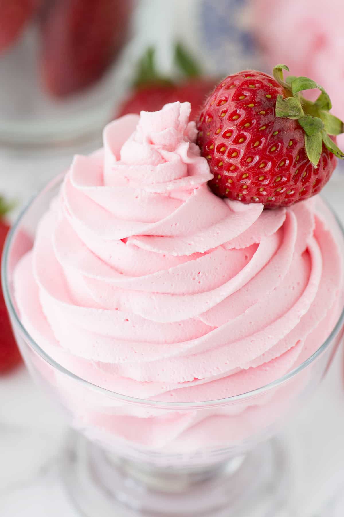 strawberry whipped cream piped into clear glass with strawberry on top