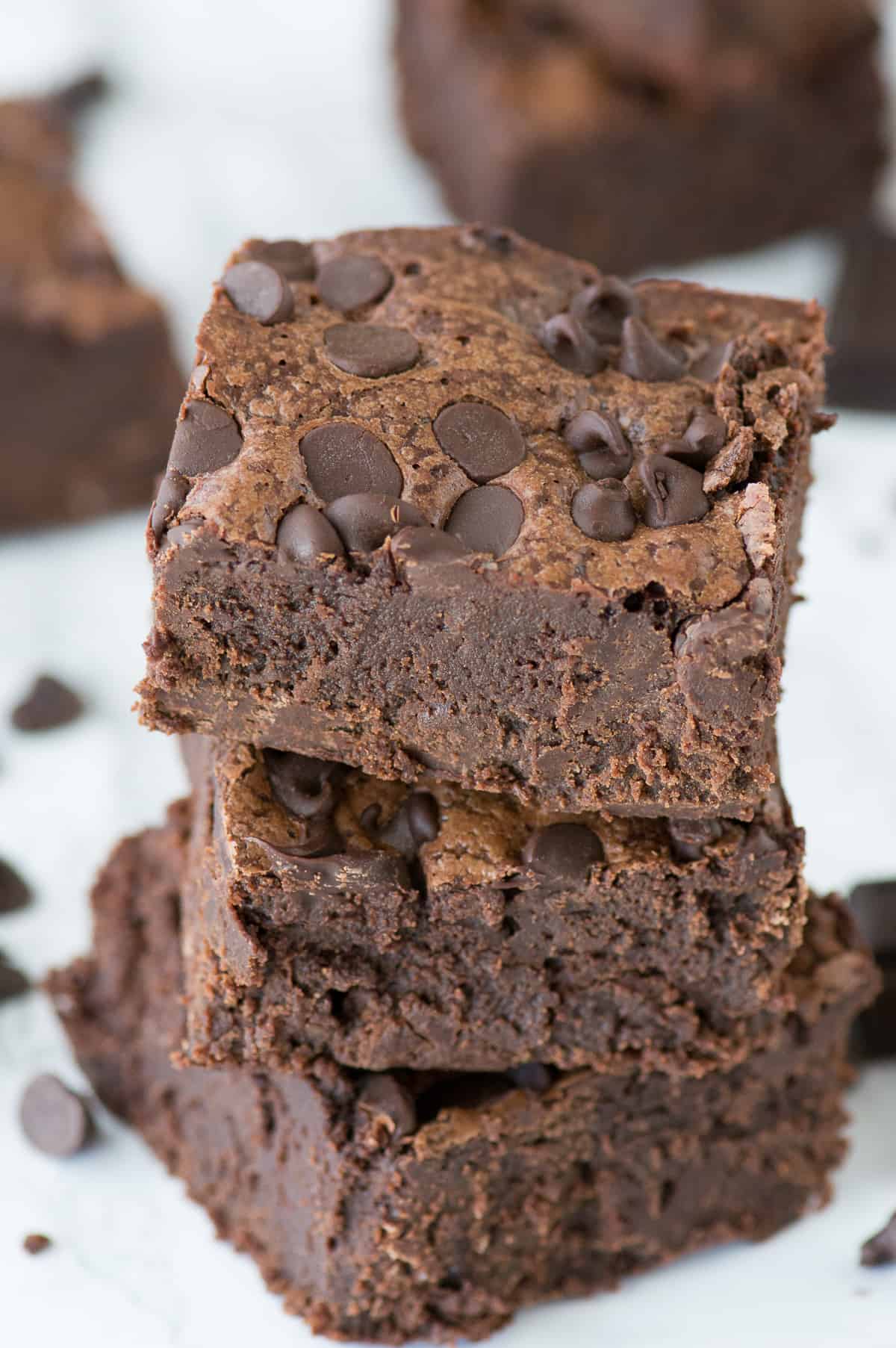 3 fudgy brownies stacked on top of each other on white background