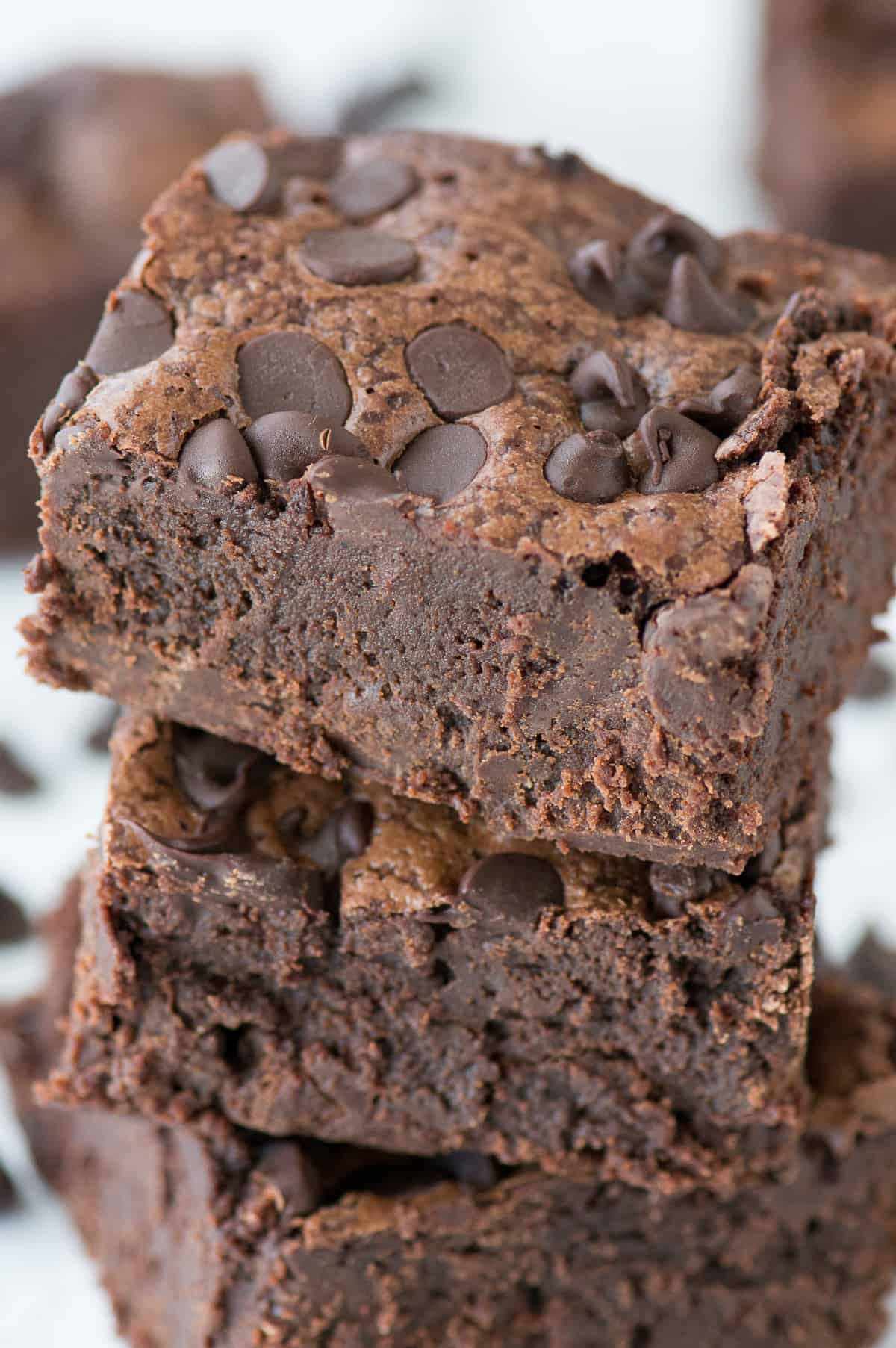 3 fudgy brownies stacked on top of each other on white background