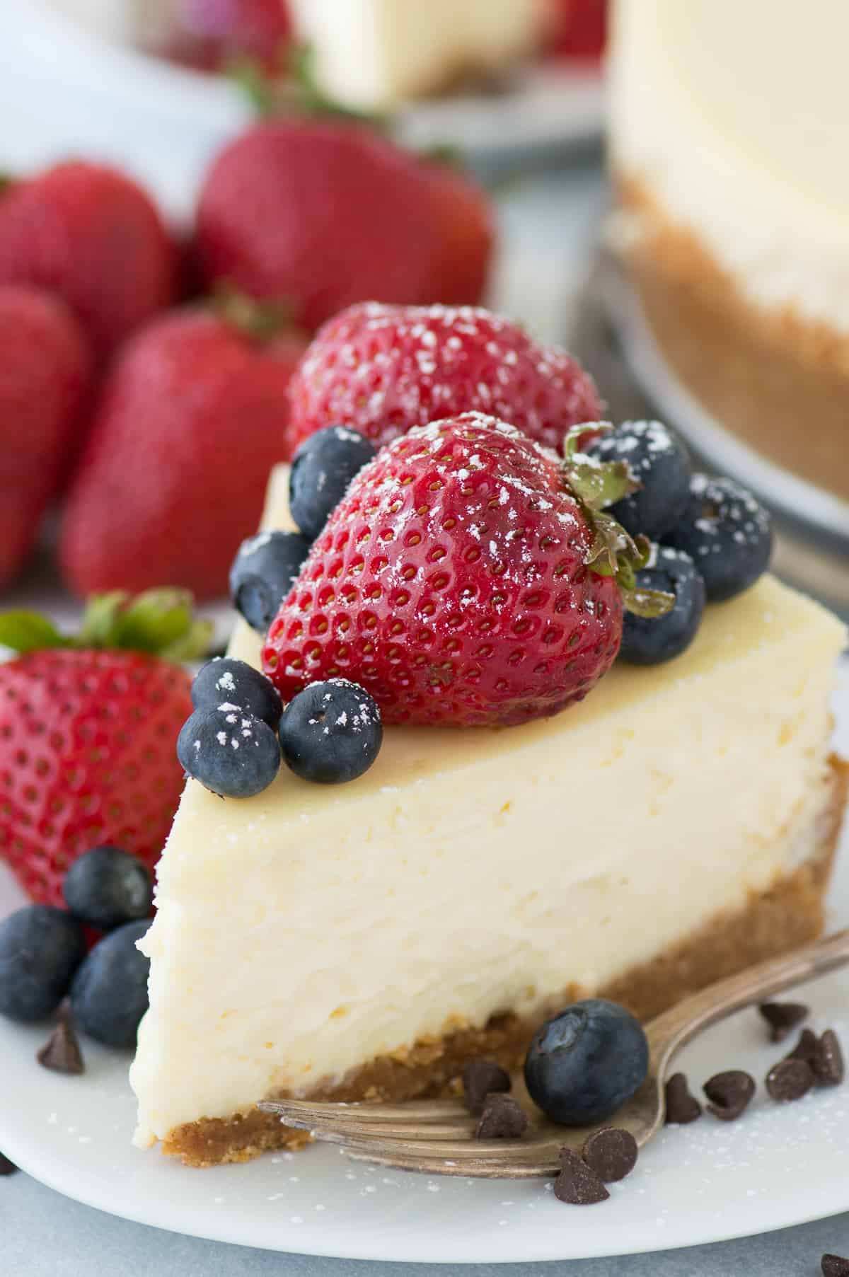 slice of classic plain cheesecake with fruit on top on white plate