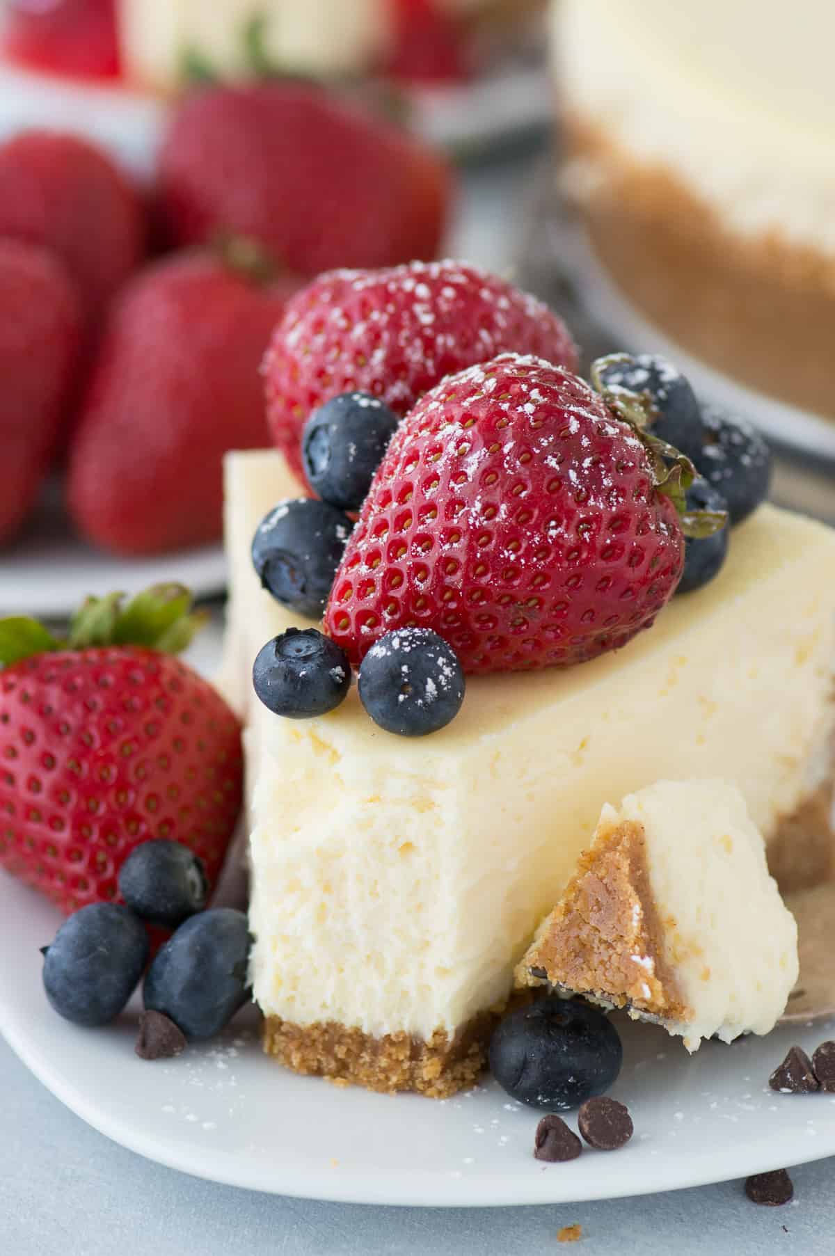 slice of classic plain cheesecake with fruit on top on white plate