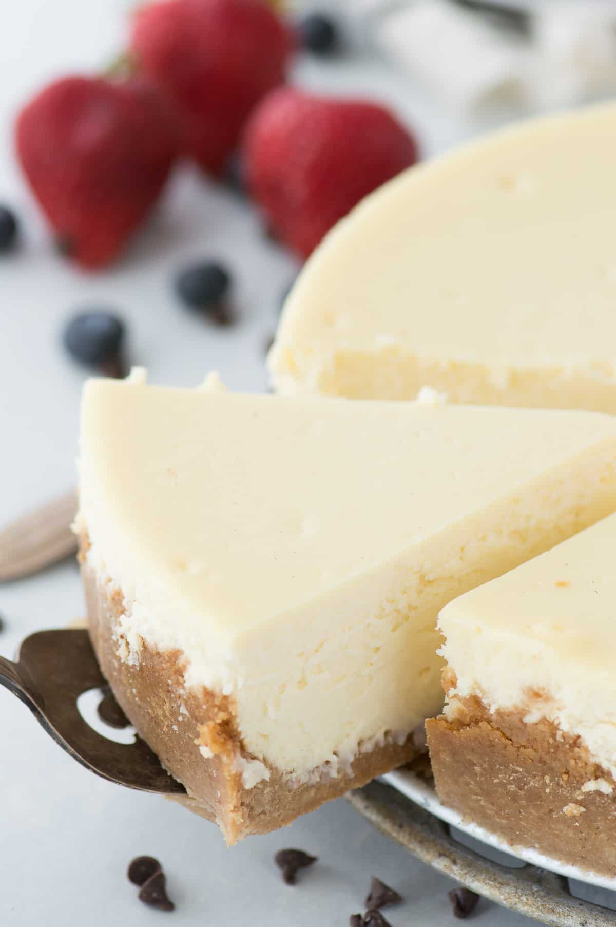 slice of classic plain cheesecake being removed from whole cheesecake