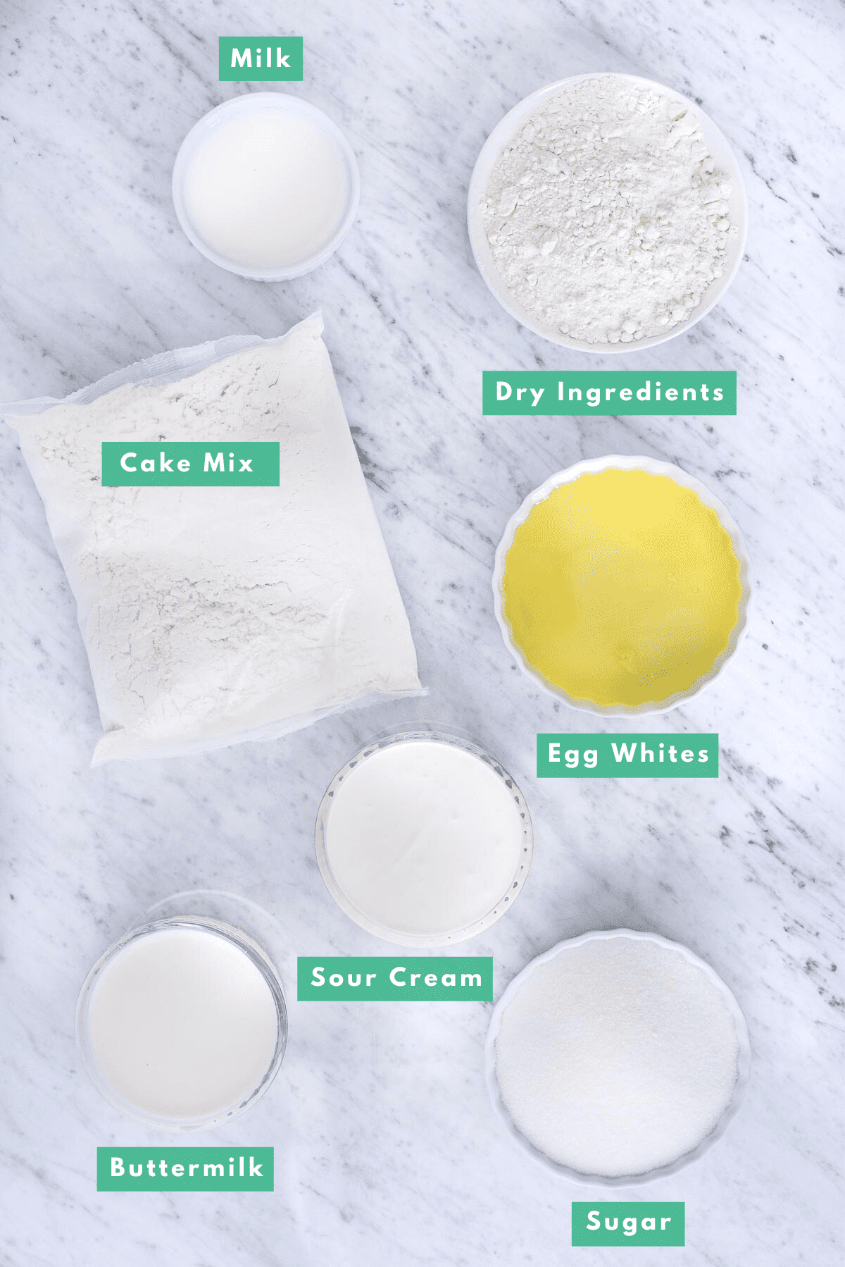 ingredients to make white cake mix from box mix on marble background with text overlay