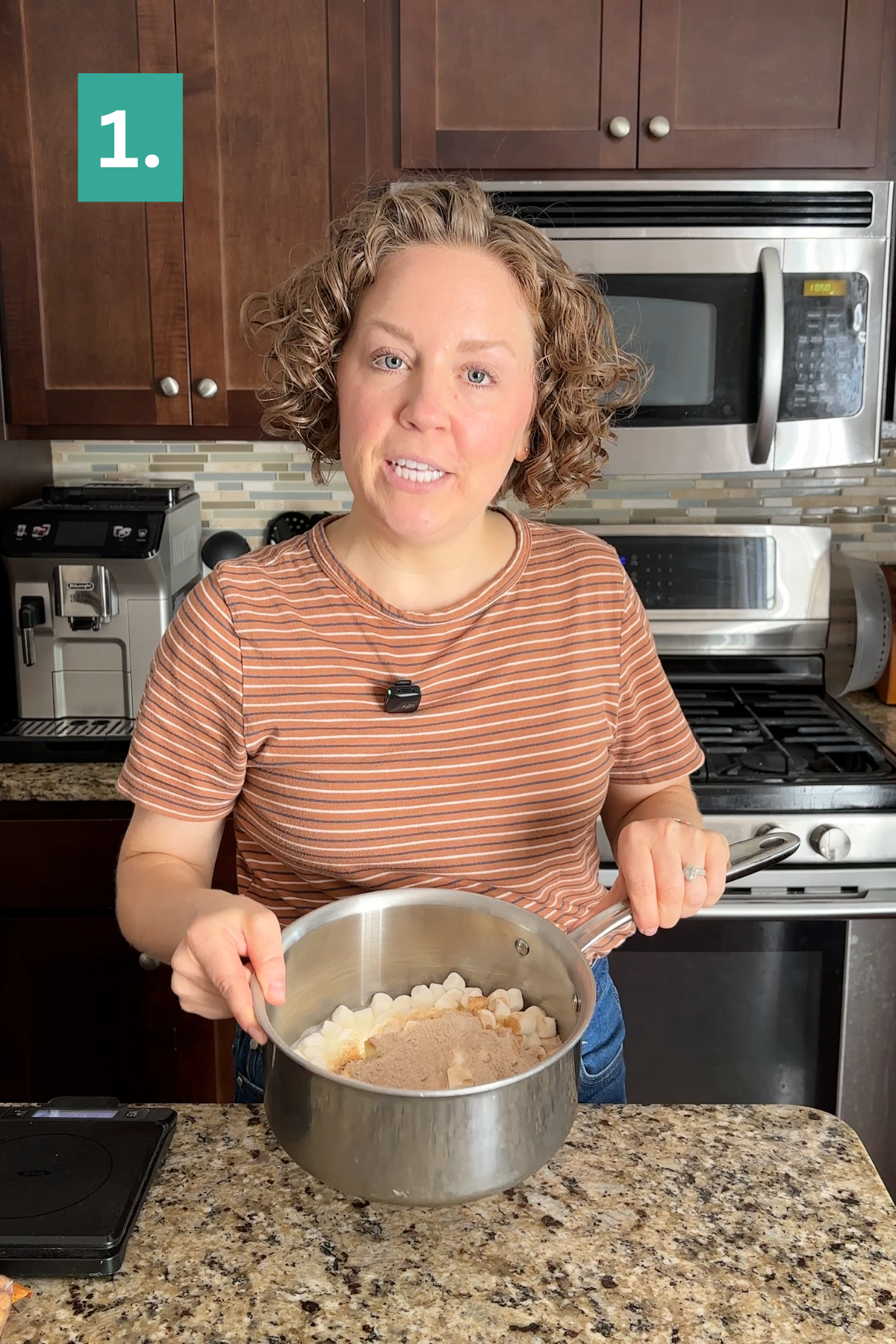 A woman in a striped shirt stands in a kitchen, smiling and holding a pot filled with marshmallows and brown sugar—the perfect base for making caramel apple fudge. A green box with the number 1 is in the top left corner of the image.