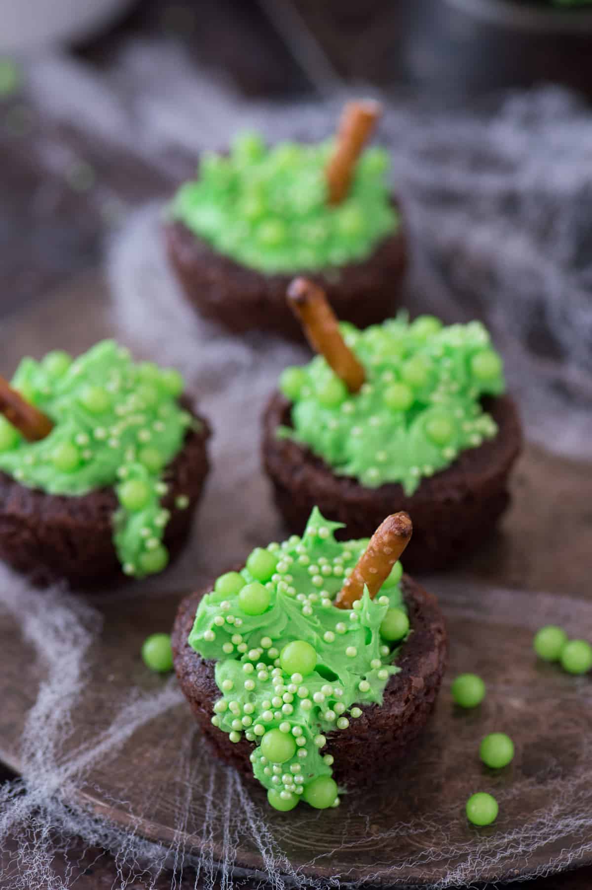 mini brownie bites filled with green frosting and green sprinkles to look like a bubbling witch's cauldron