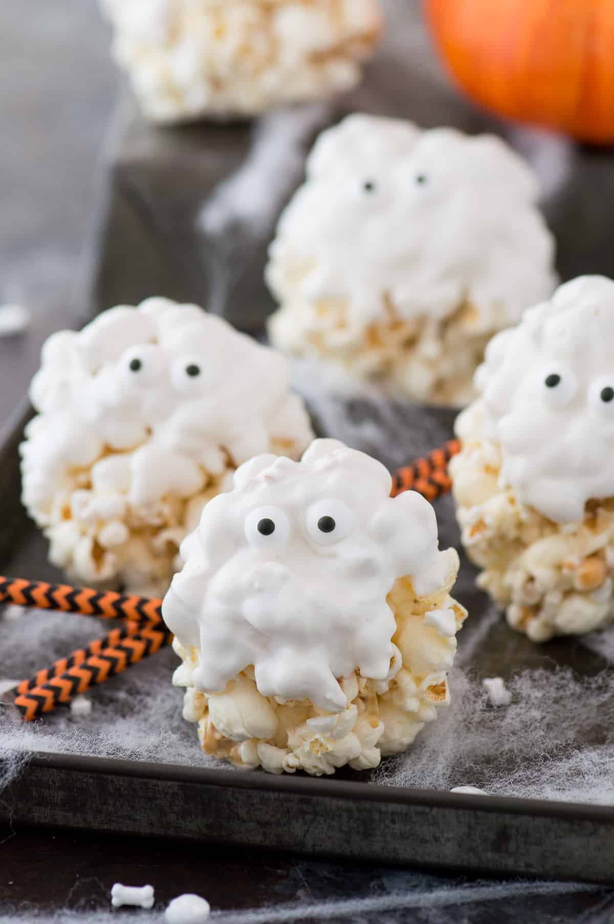 popcorn balls covered in white chocolate with candy eye balls to look like ghosts