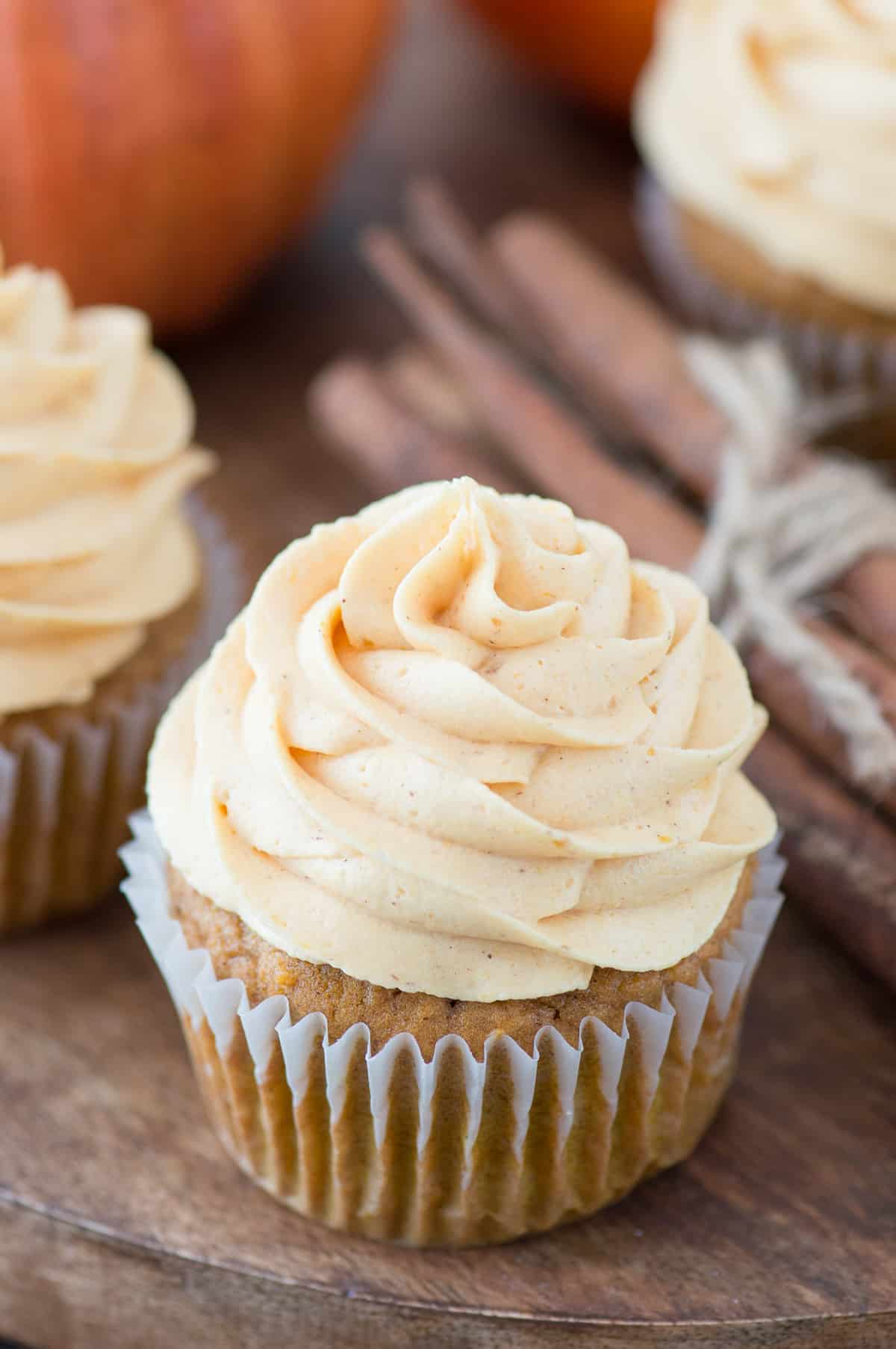 pumpkin cupcake piped with pumpkin frosting on wood background