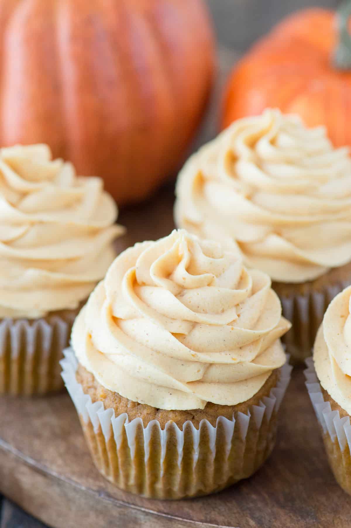 pumpkin cupcakes with pumpkin frosting on wooden tray