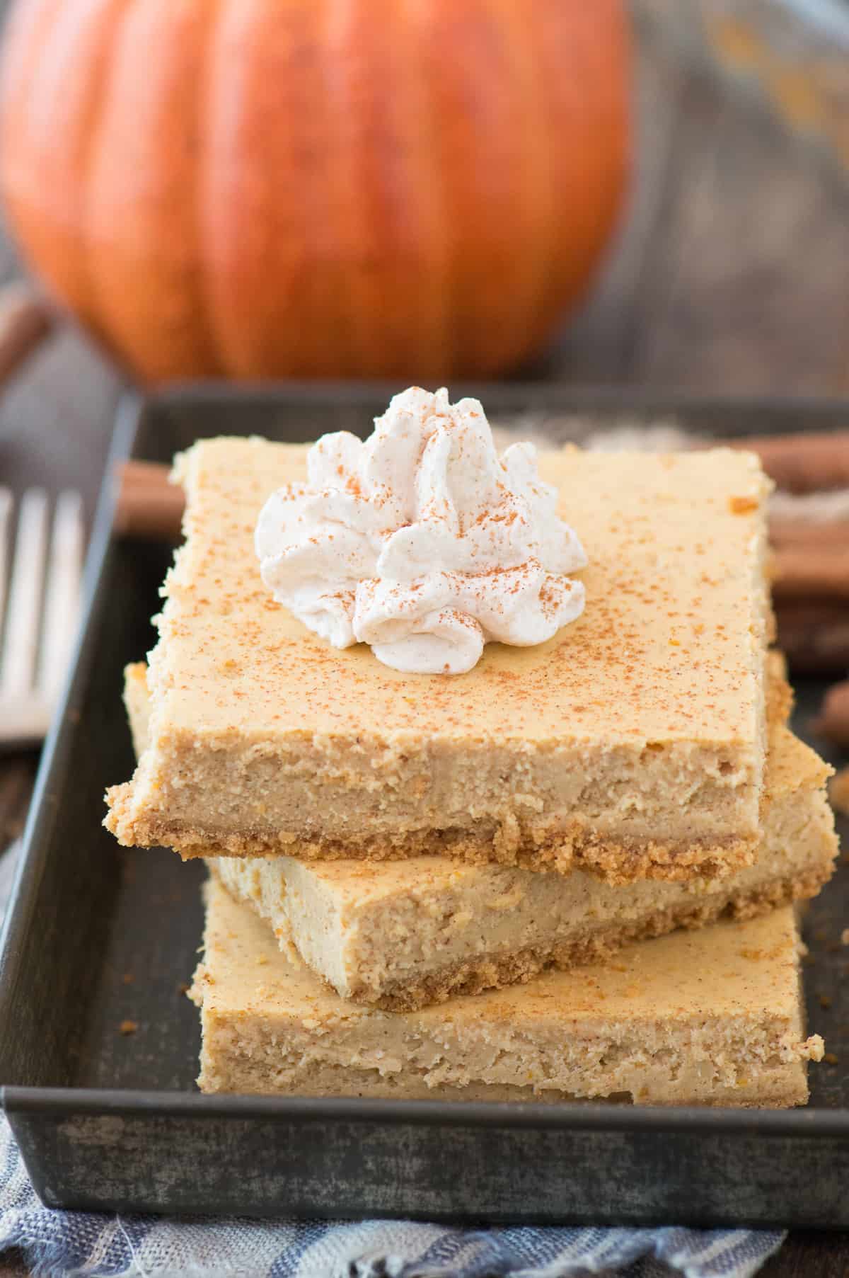 3 pumpkin cheesecake bars stacked on each other on metal tray